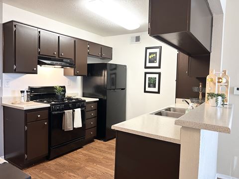 a kitchen with black appliances and a counter top and a sink