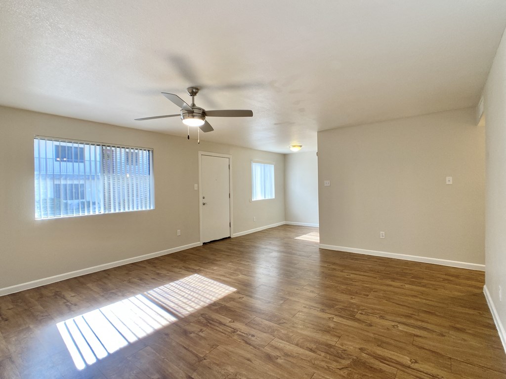 an empty living room with a ceiling fan and a window