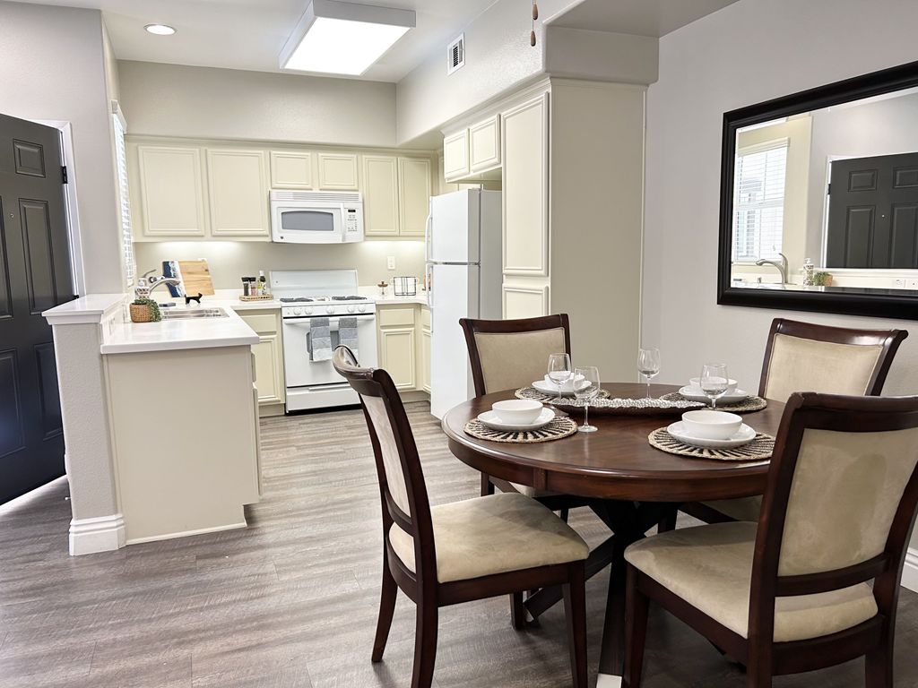 a dining area with a table and chairs and a kitchen in the background at Riverton of the High Desert Apartments, California, 92392
