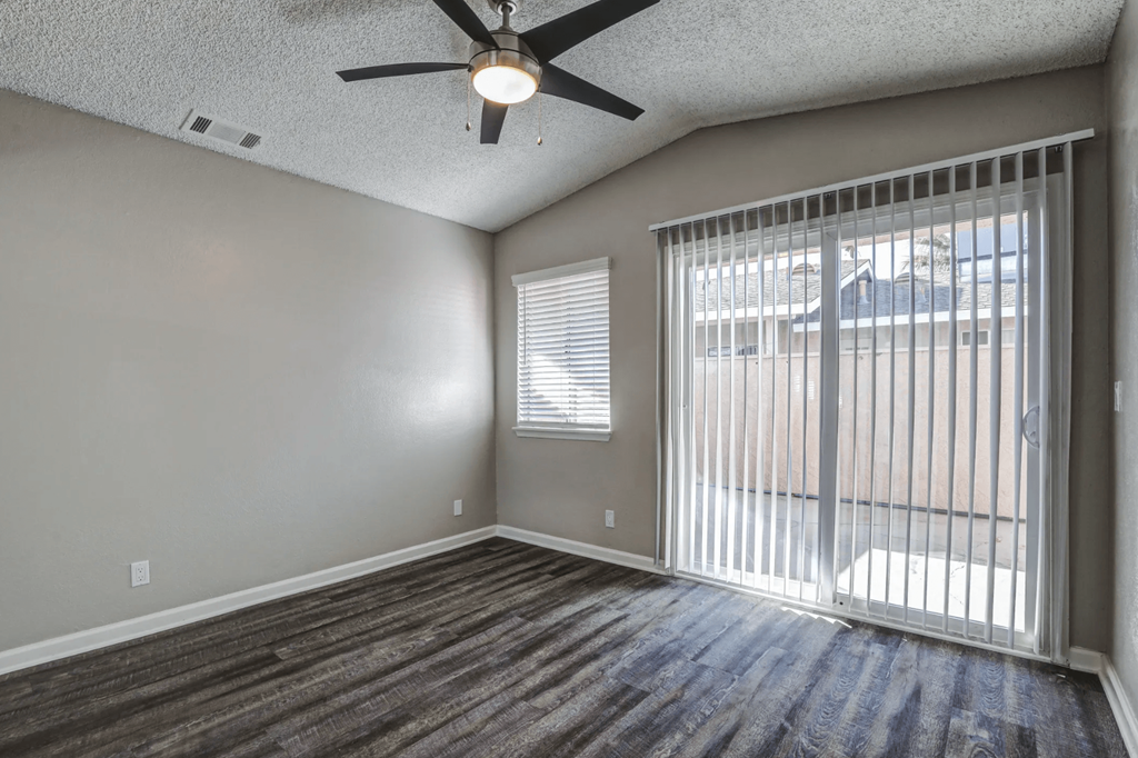 an empty living room with a large window and a ceiling fanat Aspire Seneca, Victorville