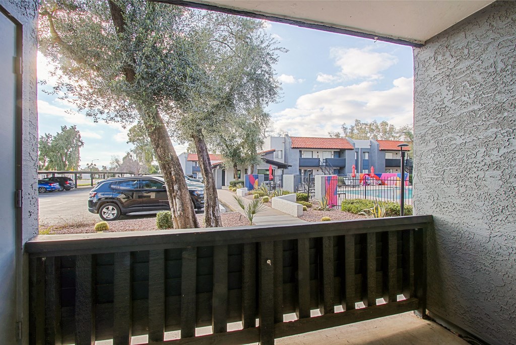 a balcony with a view of a parking lot and a tree
