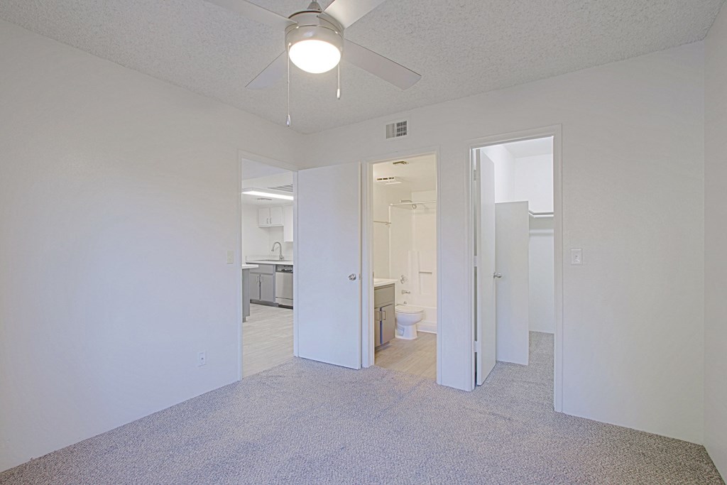 an empty living room with a ceiling fan and a bathroom