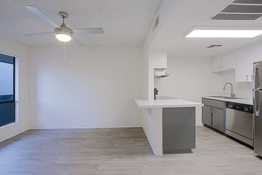 an empty kitchen with stainless steel appliances and a ceiling fan