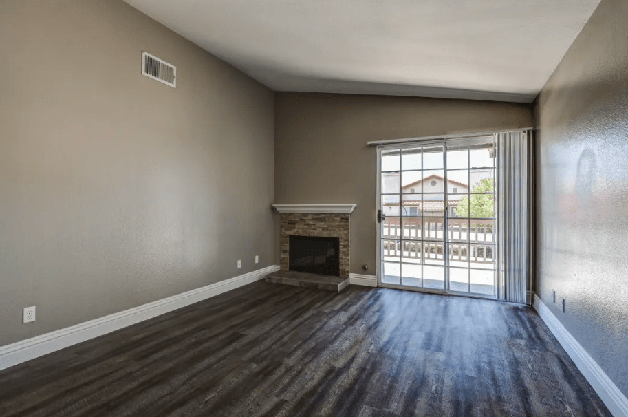 an empty living room with a fireplace and a sliding glass door at Vista Promenade Apartments, California