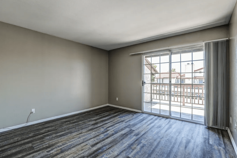 an empty living room with a sliding glass door to a balcony at Vista Promenade Apartments, Temecula, California