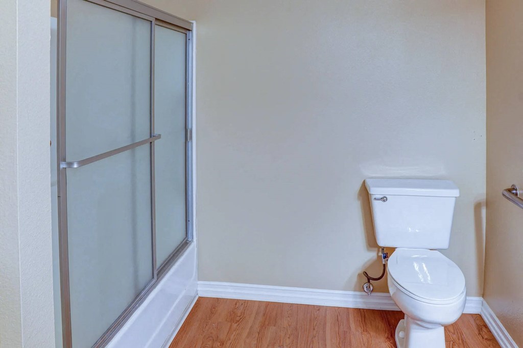 a bathroom with a toilet and a glass shower at The Arches at Regional Center West Apartments, California