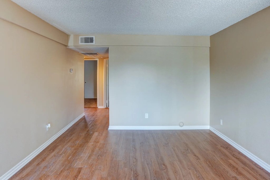 the living room and dining room of an empty house with wood floors at The Arches at Regional Center West Apartments, Palmdale, 93551