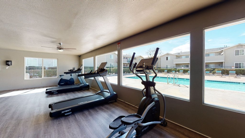 Fitness Center with Treadmills, Exercise Bike, and View of the Pool at Aspire High Desert Apartments, Victorville, 92392