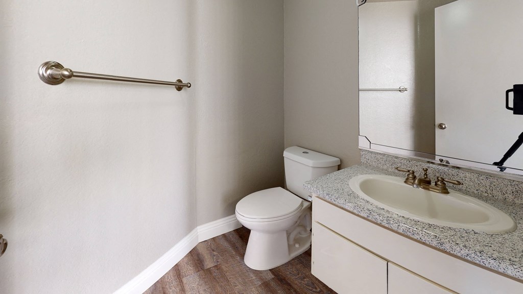 Apartments in Ontario - Rancho Vista - Bathroom With a Sleek Counter, a Sink With a Mirror, a Handtowel Rack, and a Toilet at Rancho Vista Townhomes, Ontario