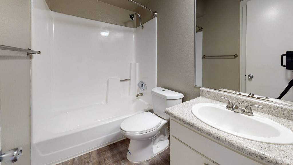 Ontario CA Apartments for Rent - Rancho Vista - Bathroom With a Large Mirror, Wood Styled Flooring, and a Toilet With an adjacent Shower at Rancho Vista Townhomes, California