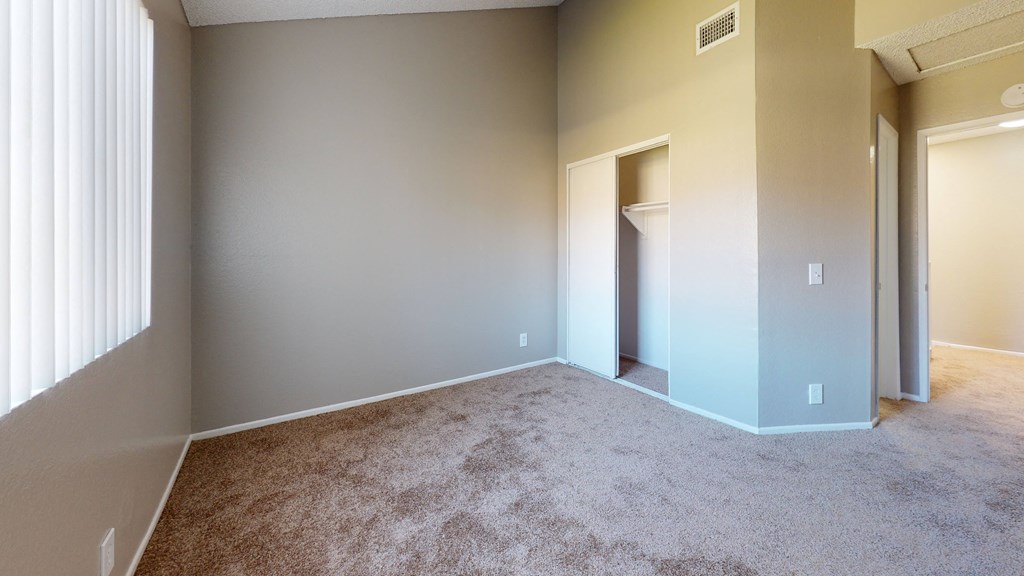 Unfurnished Bedroom With Carpet Flooring, a Window With Shutters, and a Closet in the Corner at Rancho Vista Townhomes, California, 91764