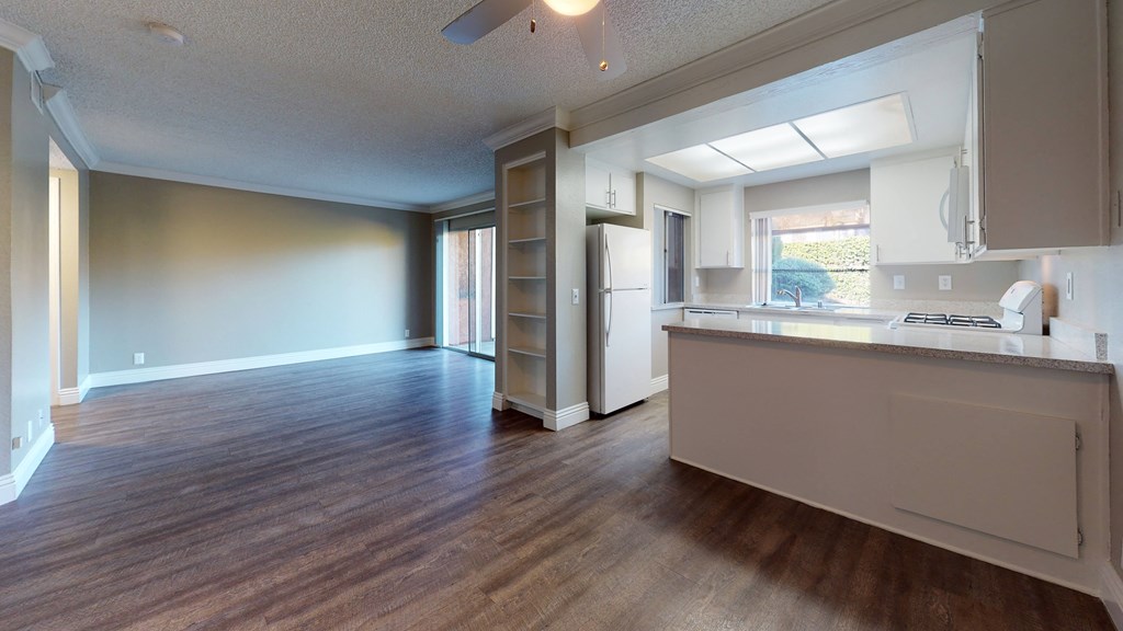 Apartments Ontario - Rancho Vista - Unfurnished Dining Area With Wooden Flooring, a Ceiling Fan, and Shelving Between the Rooms at Rancho Vista Townhomes, Ontario, CA