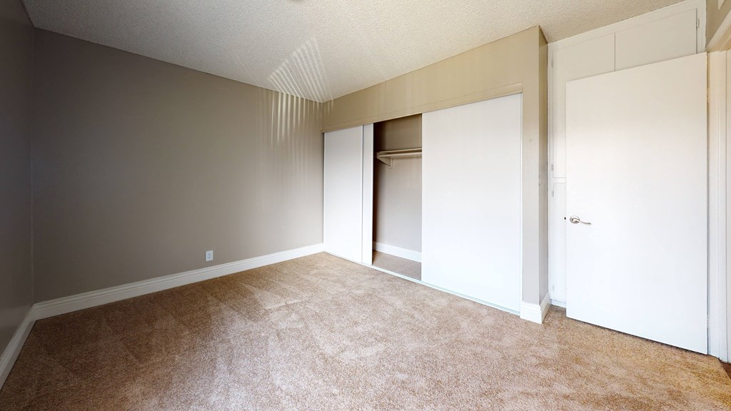 Plush Carpeted Bedroom with Sliding Closet Doors and White Walls at Avante Apartments, Ontario, California