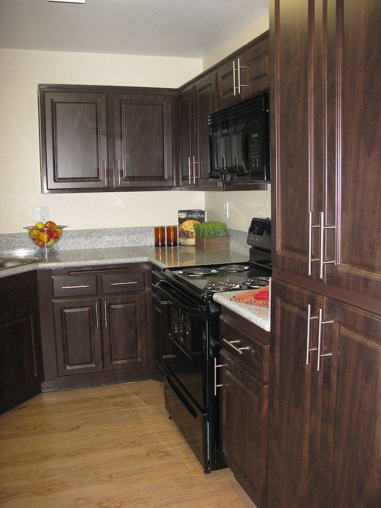 Apartments for Rent in Antelope Valley, CA - The Arches at Regional Center West Kitchen with Black Appliances, Granite Countertops, Plank Flooring, and Dark Mocha Cabinets - Photo Gallery 1