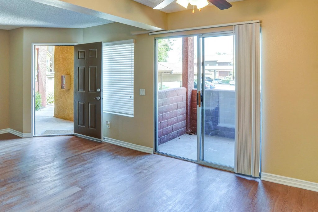 an empty living room with sliding glass doors to a patio at The Arches at Regional Center West Apartments, Palmdale