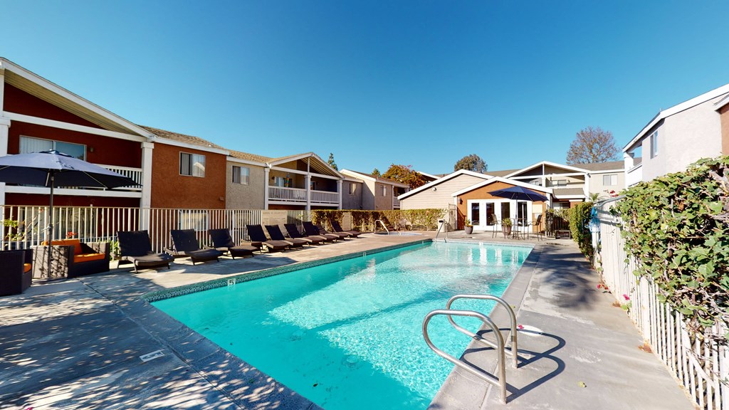 Apartment Ontario CA - Rancho Vista - Outdoor Pool With Clear Water, Lounge Chairs, Additional Seating With Umbrellas, and a Fenced Perimeter at Rancho Vista Townhomes, California