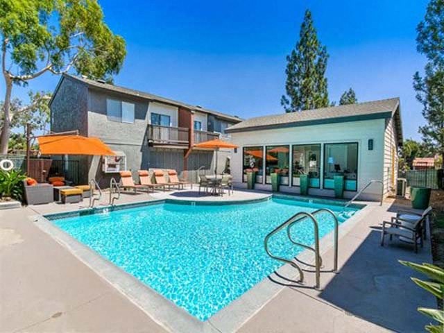 Pool With Lounge Chairs, Umbrellas, Trees, And Clubhouse at Encore Apartments, California