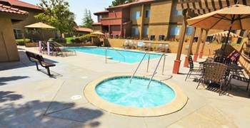 Sparkling Swimming Pool and Spa The Arches at Regional Center West Apartments in Antelope Valley, CA - Sparkling Swimming Pool and Spa Surrounded by Lounge Chairs with Covered Tables - Photo Gallery 4