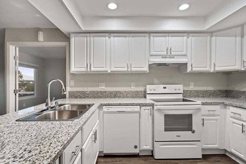 a white kitchen with white appliances and granite counter tops
