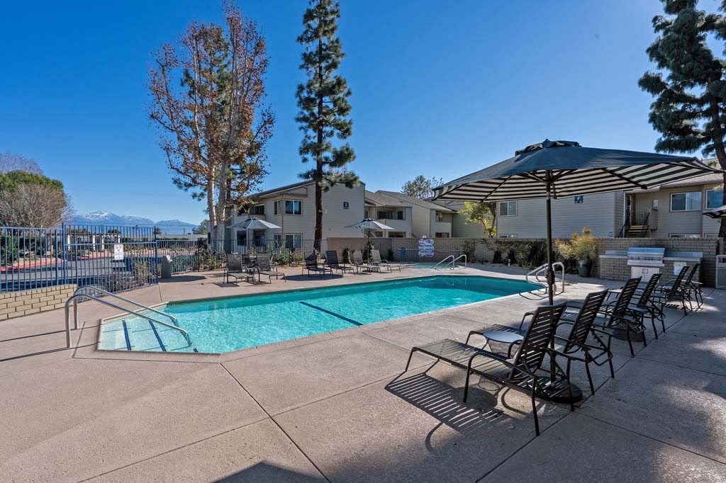 a swimming pool with chaise lounge chairs and umbrellas at Aspire Rialto, Rialto