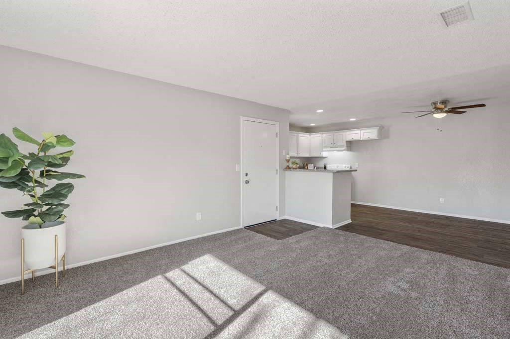 a living room with a ceiling fan and a kitchen in the background at Aspire Rialto, Rialto California