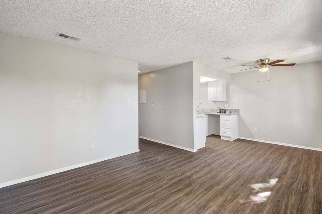 a living room with a ceiling fan and a kitchen in the background at Aspire Redlands, California