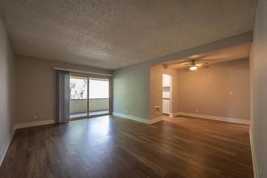 an empty living room with a wood floor and a ceiling fan at Aspire Upland Apartments, California