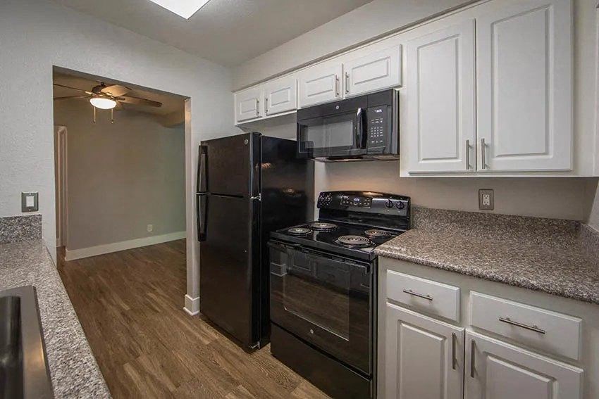 a kitchen with black appliances and white cabinets at Aspire Upland Apartments, Upland, CA, 91786