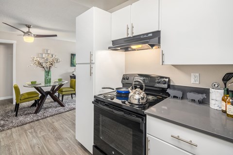 A modern kitchen with a black stove top oven and white cabinets.