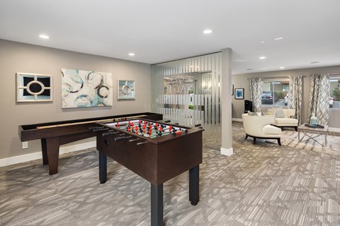 A pool table is in the middle of a room with a chair and a painting on the wall.