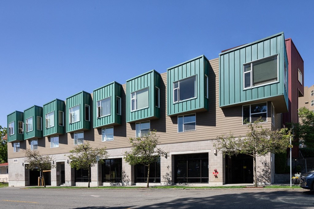 a row of apartment buildings with green and brown roofs on a city street