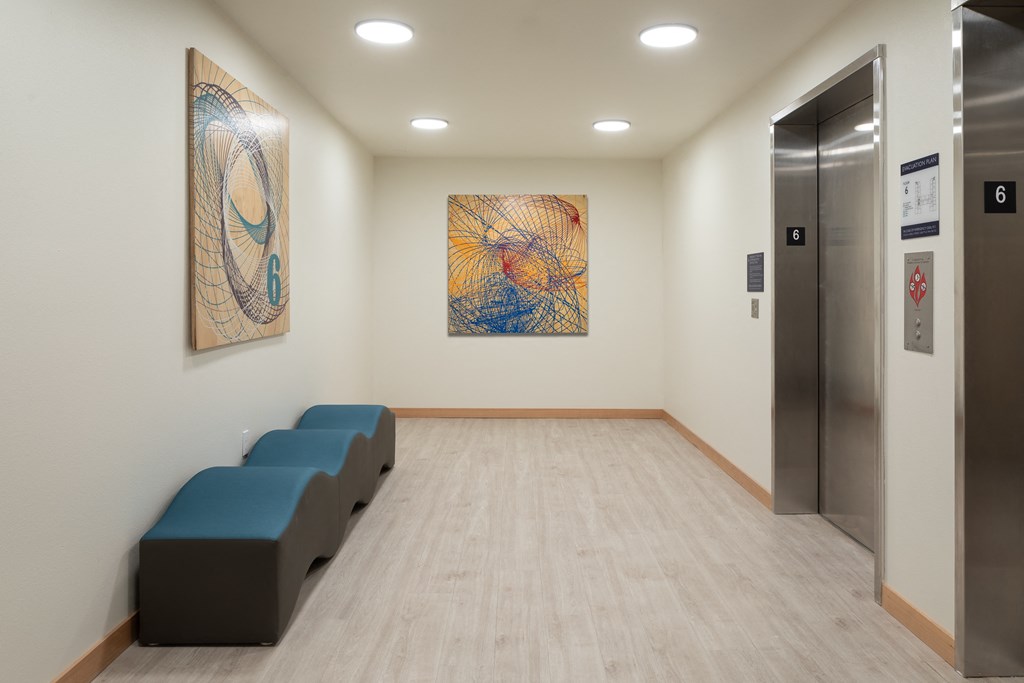 a waiting room with two blue benches and two paintings on the wall