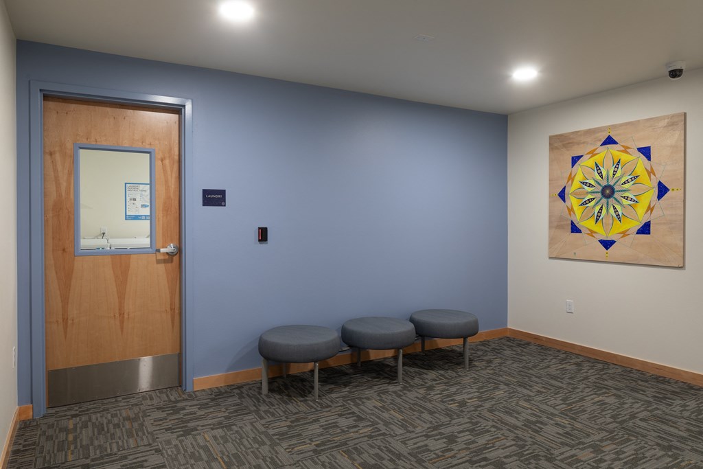 a room with three stools and a painting on the wall and a door to