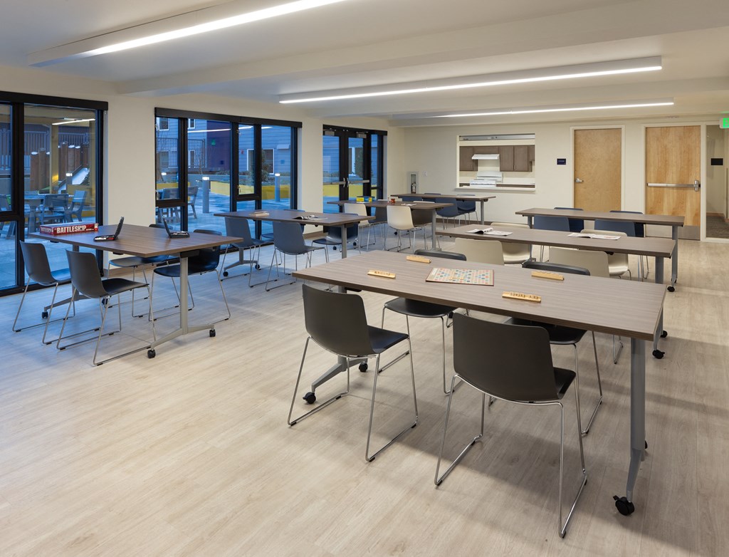 a large classroom with tables and chairs and a kitchen