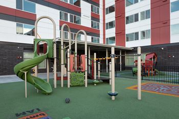 A playground with a green slide and a red and green playhouse.