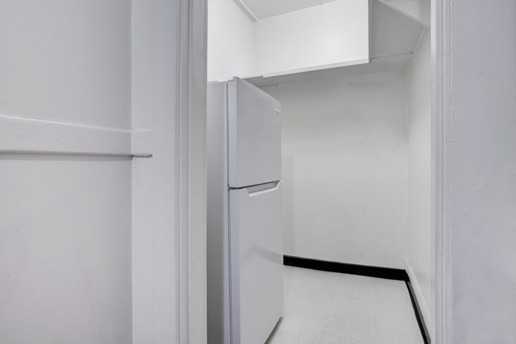 A white refrigerator is in a small kitchen.