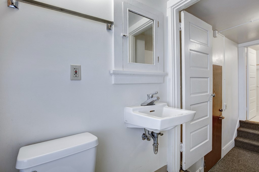 A white bathroom with a toilet, sink, and medicine cabinet.