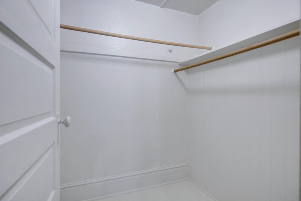 A white closet with a shelf and a door.