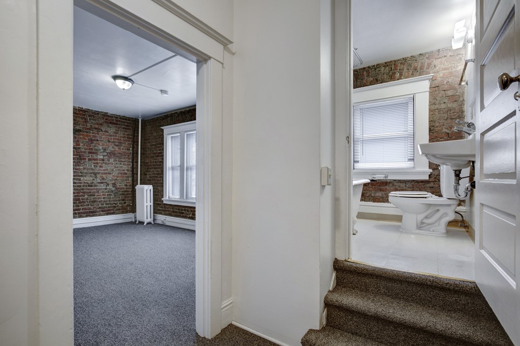 A bathroom with a brick wall and a window.