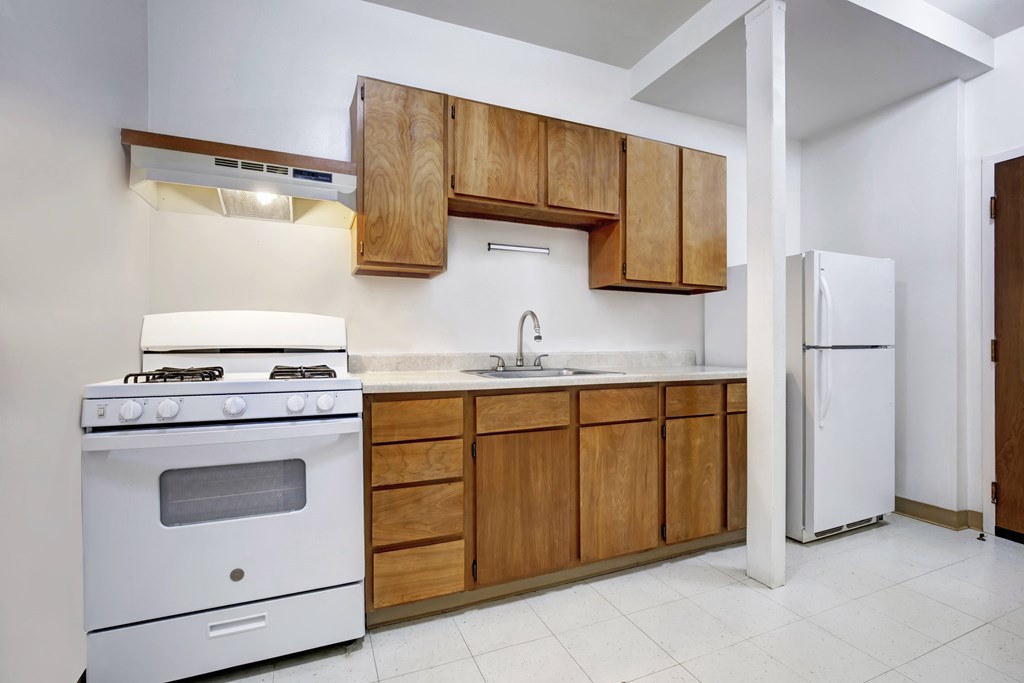 A kitchen with a white stove and wooden cabinets.