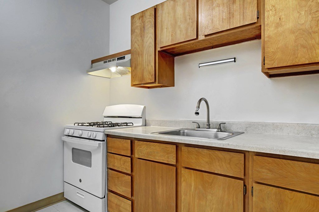 A kitchen with a white stove and wooden cabinets.