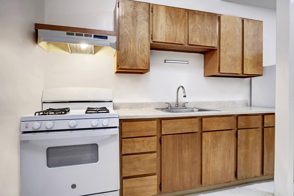 A white stove and sink in a kitchen with wooden cabinets.