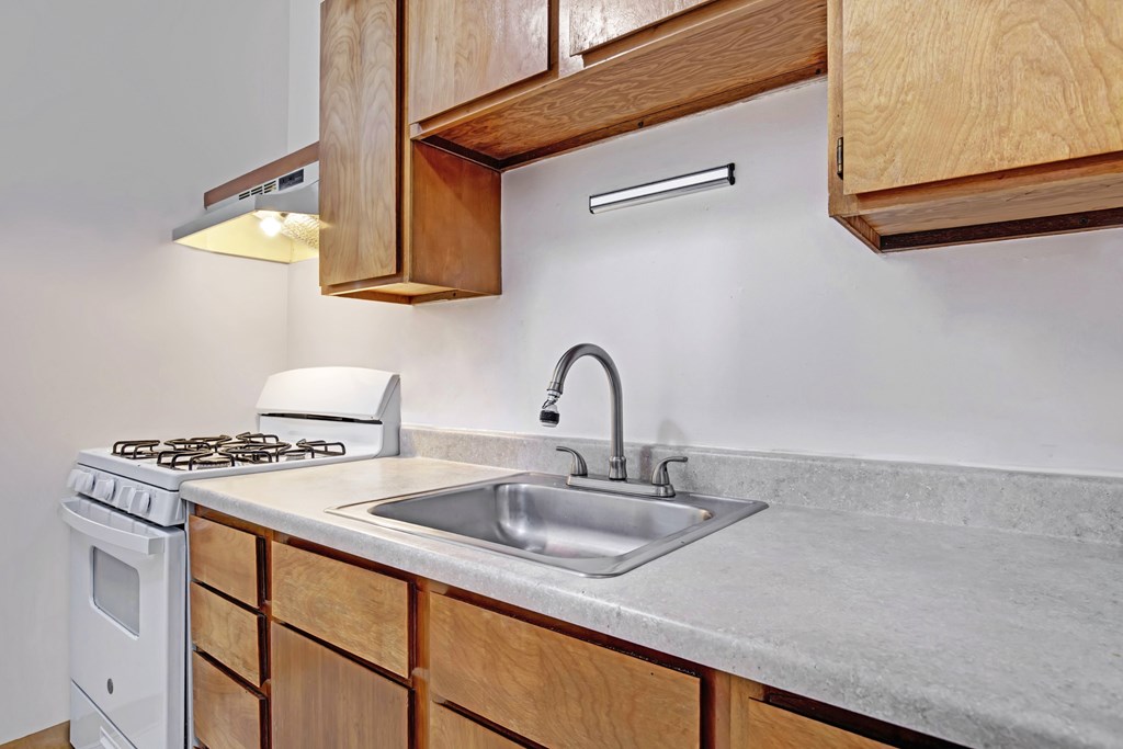 A kitchen with a white stove and a white sink.