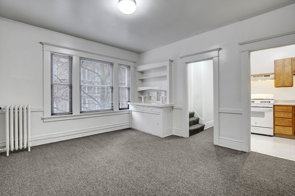 A white room with a grey carpet and a white radiator.