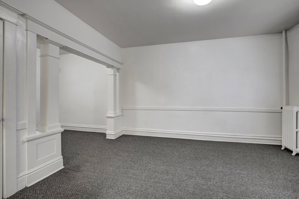 A room with white walls and a grey carpet.
