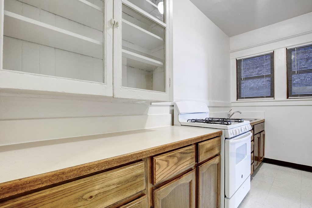 A kitchen with wooden cabinets and a white stove top oven.