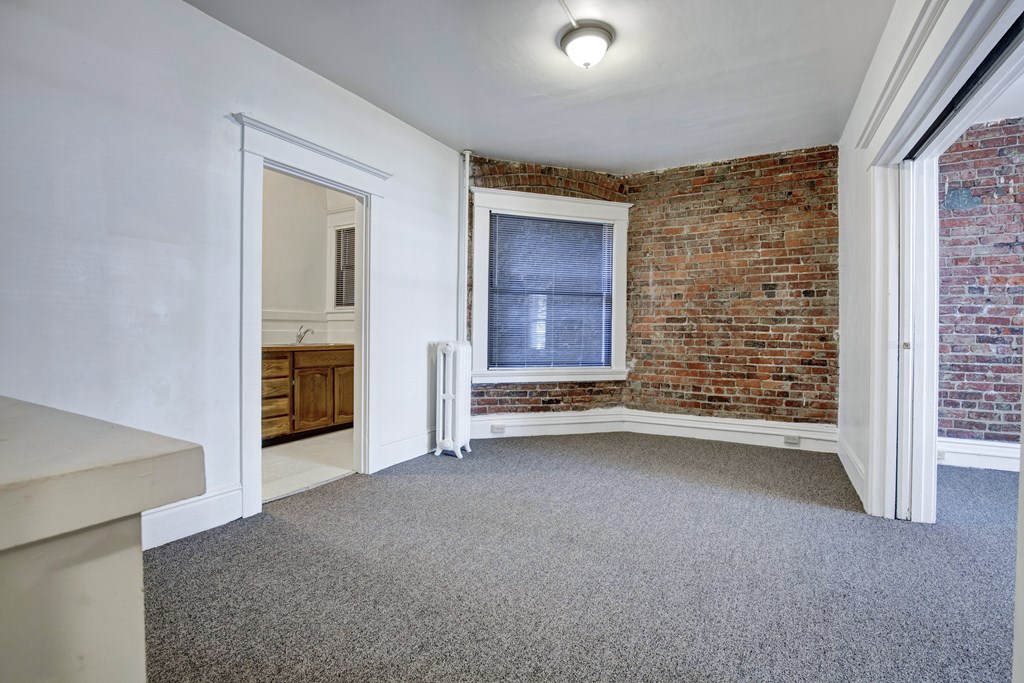 A room with a brick wall and a window.