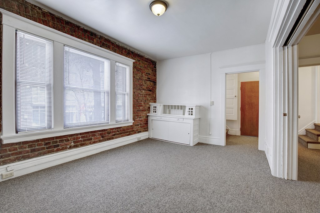 A room with a white cabinet and a window with blinds.