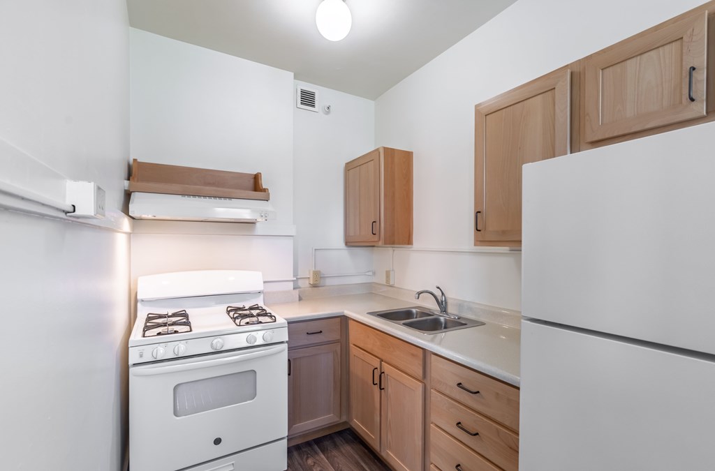 A small kitchen with white appliances and wooden cabinets.