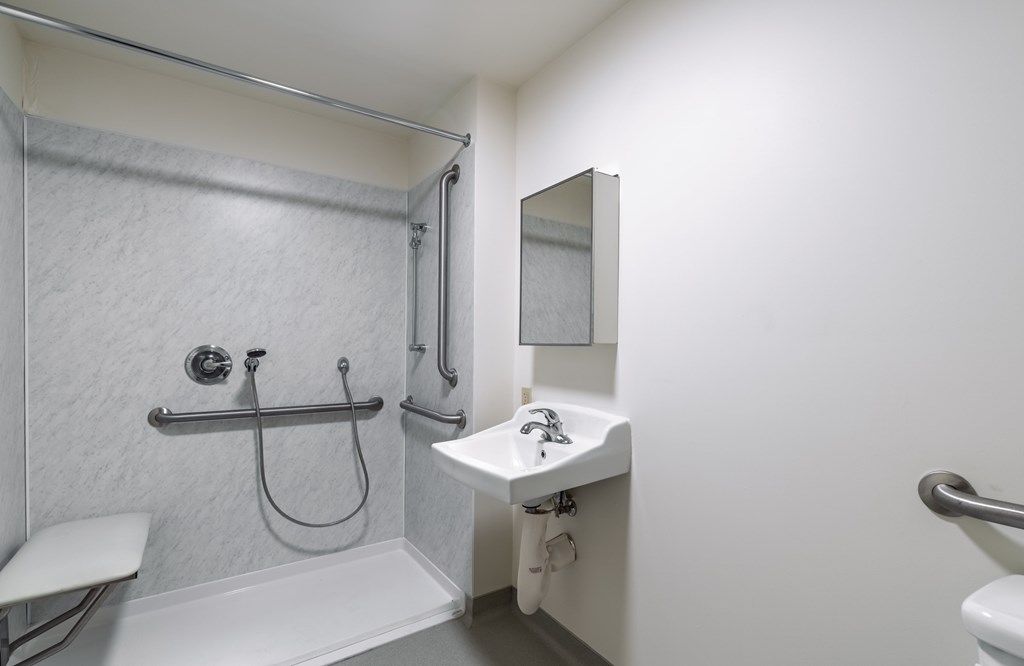 A white bathroom with a shower, sink, and toilet.